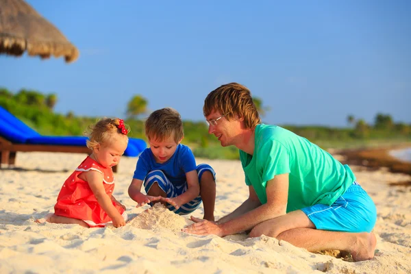 Padre y dos niños jugando con arena en la playa —  Fotos de Stock