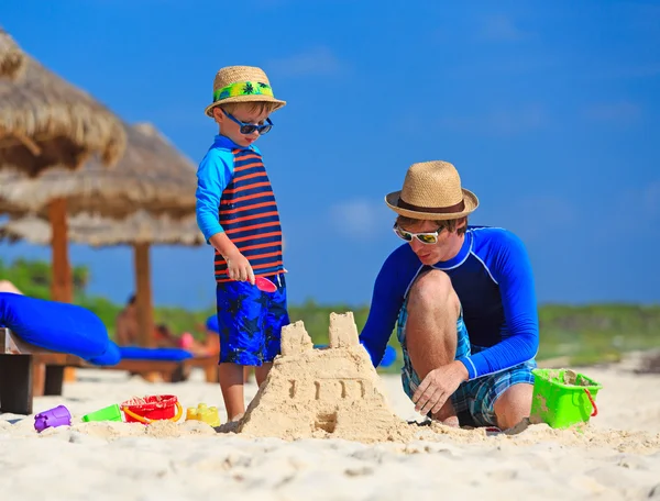 Vader en zoon gebouw zand kasteel op het strand — Stockfoto