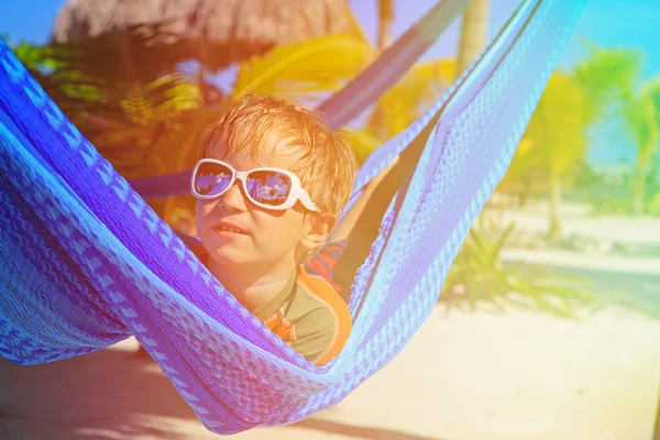 Menino feliz relaxado em rede na praia — Fotografia de Stock