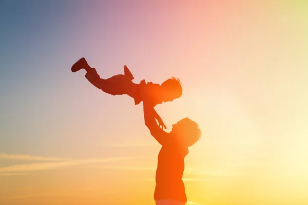 Father and little son silhouettes play at sunset — Stock Photo, Image