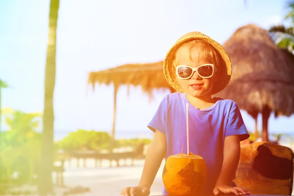 Malý chlapec pití kokosový koktejl na pláži — Stock fotografie