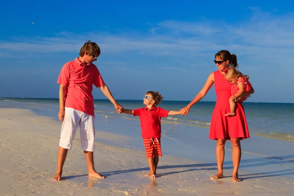 Jeune famille avec deux enfants marchant à la plage — Photo