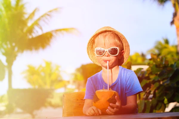Malý chlapec pití kokosový koktejl na pláži — Stock fotografie