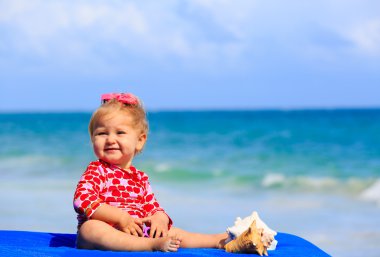 Sahilde deniz kabuklarını ile sevimli küçük kız