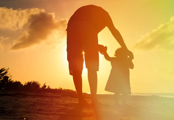 Pai e filha caminhando na praia ao pôr do sol — Fotografia de Stock