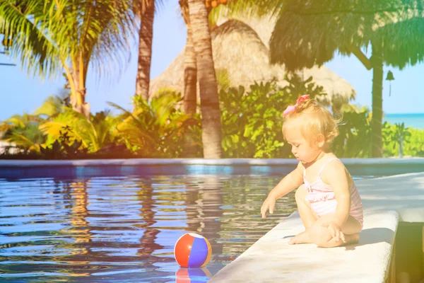Menina bonito brincando com bola na piscina — Fotografia de Stock