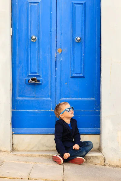 Mignon petit garçon à l'extérieur contre porte bleue — Photo