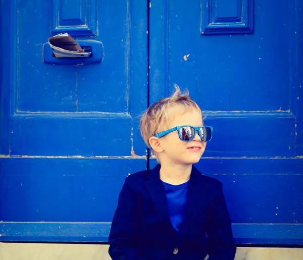Menino bonito ao ar livre contra a porta azul — Fotografia de Stock