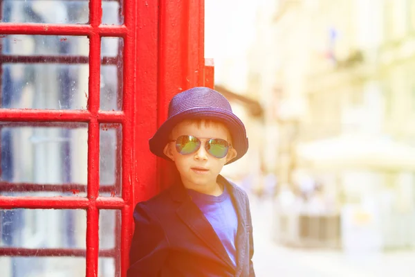 Liten pojke med röd telefon låda i staden — Stockfoto