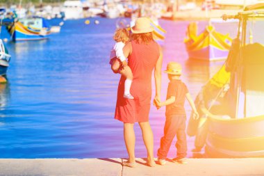 Anne ve çocuklar Malta'da geleneksel tekneler bakarak