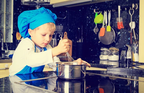 Menino gosta de cozinhar na cozinha — Fotografia de Stock