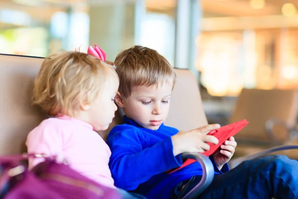 Niños mirando almohadilla táctil mientras viajan en el aeropuerto —  Fotos de Stock