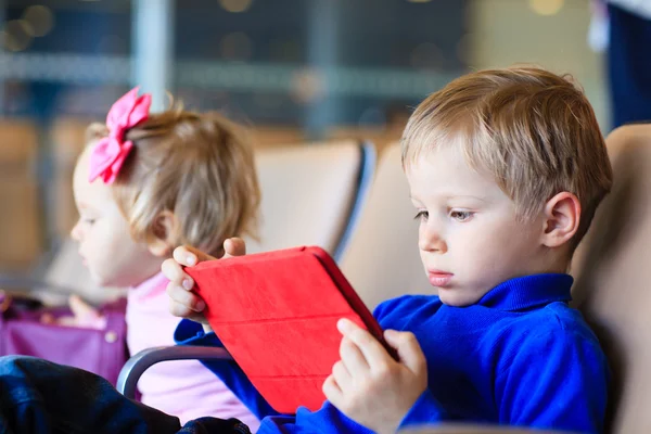 Kleiner Junge schaut auf Touchpad am Flughafen — Stockfoto