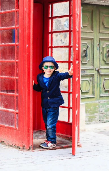 Petit garçon avec cabine téléphonique rouge dans la ville — Photo
