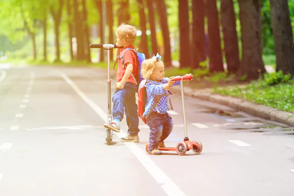 Due bambini ragazzo e ragazza equitazione scooter in città — Foto Stock