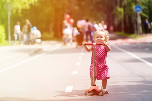 Счастливая маленькая девочка учится ездить на скутере по городу — стоковое фото