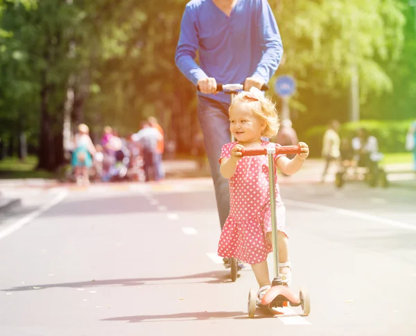 Счастливые девочка и отец на скутерах в городе — стоковое фото