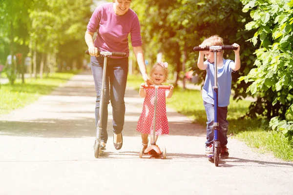 Mutter mit Kindern fährt im Sommer Roller — Stockfoto