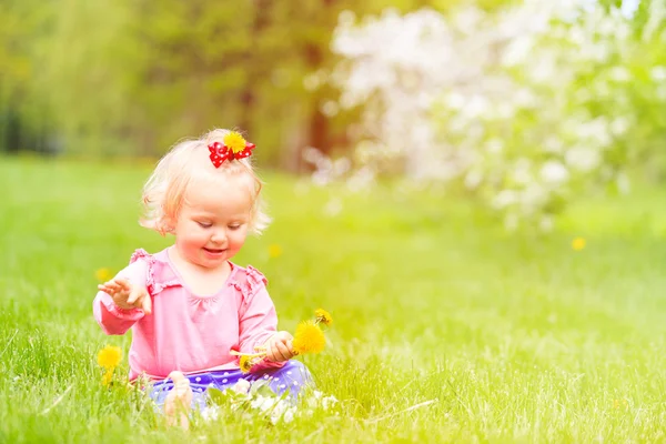 Schattig klein meisje met bloemen in de lente natuur — Stockfoto