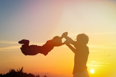 Baba ve oğul siluetleri günbatımında oynamak