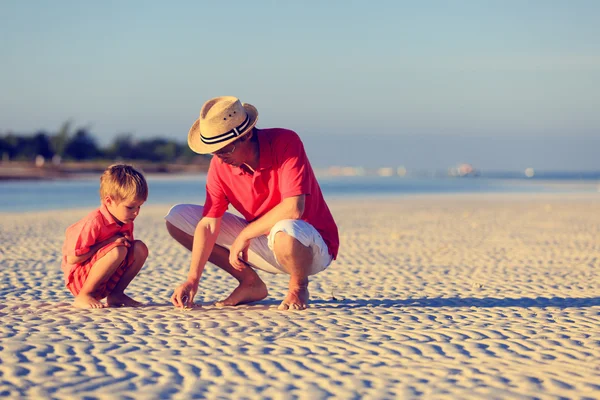 Father and son collecting seashells on summer beach — Stock Photo, Image