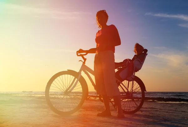 Silhueta de mãe e bebê de bicicleta ao pôr do sol — Fotografia de Stock