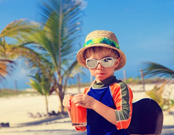 Carino piccolo ragazzo bere succo sulla spiaggia — Foto Stock