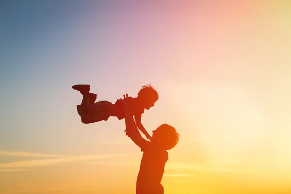 father and son silhouettes play at sunset