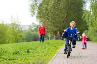 mutlu çocuklar scooter ve parkta Bisiklete binme