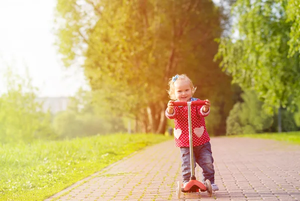 Linda niña montando scooter en el parque de verano — Foto de Stock