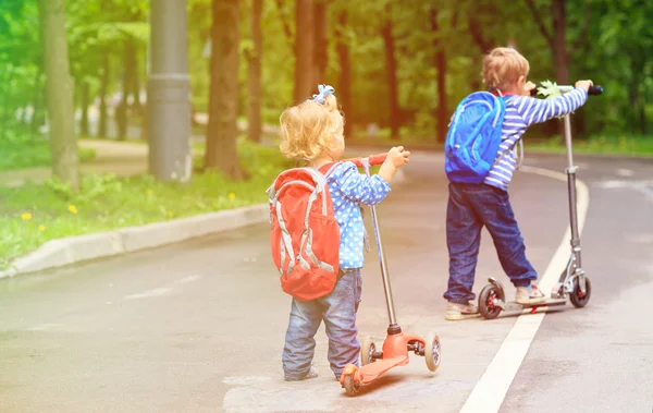 little boy and toddler girl riding scooters in the city