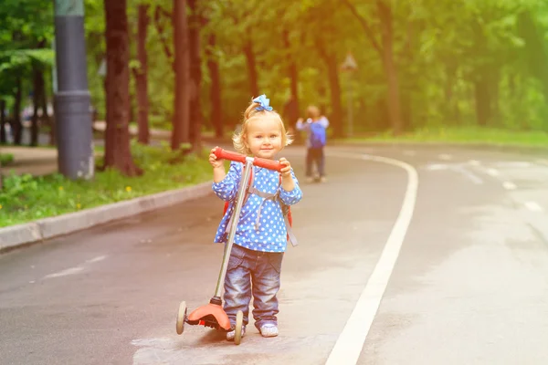 Piccolo ragazzo e bambino ragazza equitazione scooter in città — Foto Stock