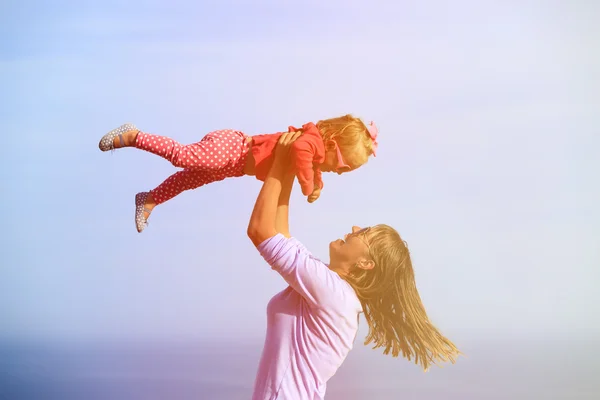 Moeder en gelukkig dochtertje spelen op sky — Stockfoto