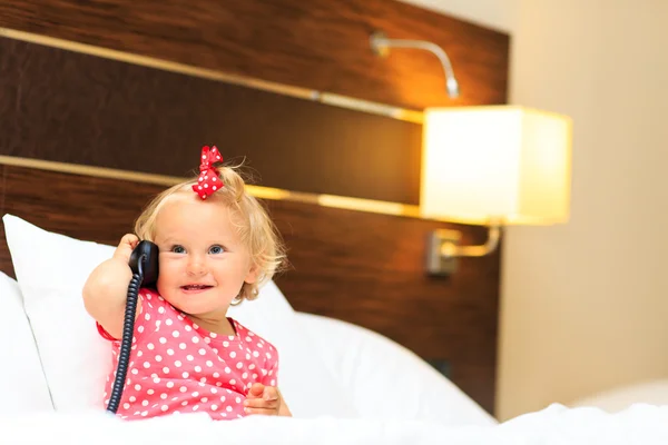 Söt liten flicka med i telefon i hotellrum — Stockfoto