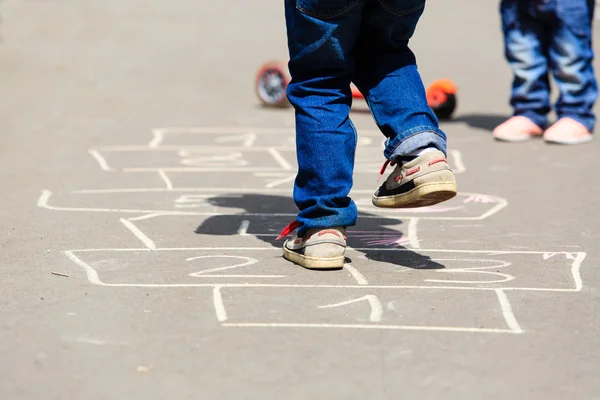 Niños jugando hopscotch en el patio al aire libre —  Fotos de Stock