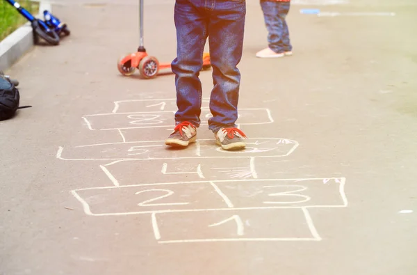 Niños jugando hopscotch en el patio al aire libre — Foto de Stock