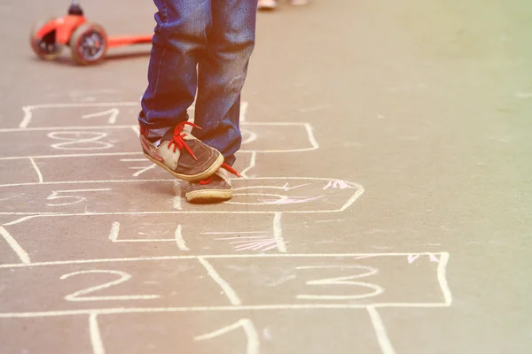 Pequeno menino jogar hopscotch ao ar livre — Fotografia de Stock