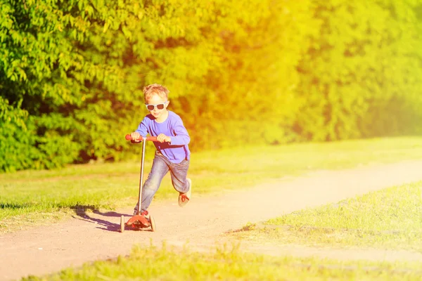 夏の公園で小さな少年乗馬スクーター — ストック写真