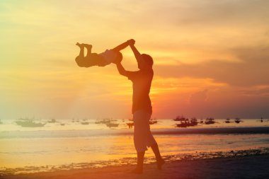 Baba ve oğul siluetleri günbatımında oynamak