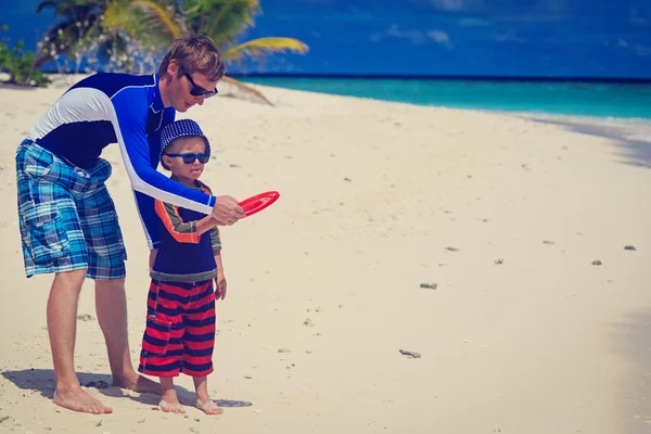 Отец и сын играют с летающим диском на пляже — стоковое фото