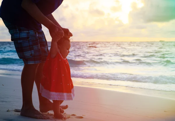 Vader en dochtertje lopen op sunset beach — Stockfoto