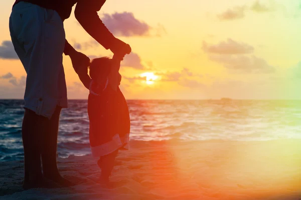 Vater und kleine Tochter spazieren am Sonnenuntergangsstrand — Stockfoto