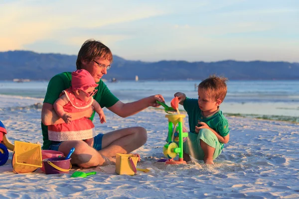 Отец с двумя детьми играет на песчаном пляже — стоковое фото