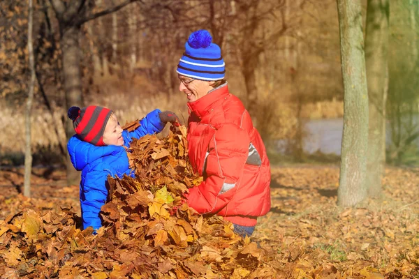 Apa és fia játszik az őszi levelek — Stock Fotó
