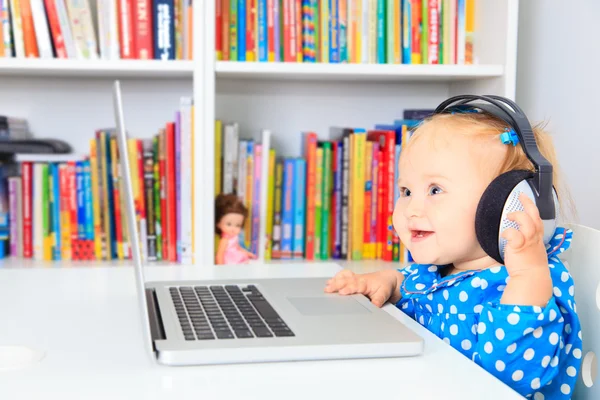 Kleines Mädchen mit Kopfhörer und Laptop — Stockfoto