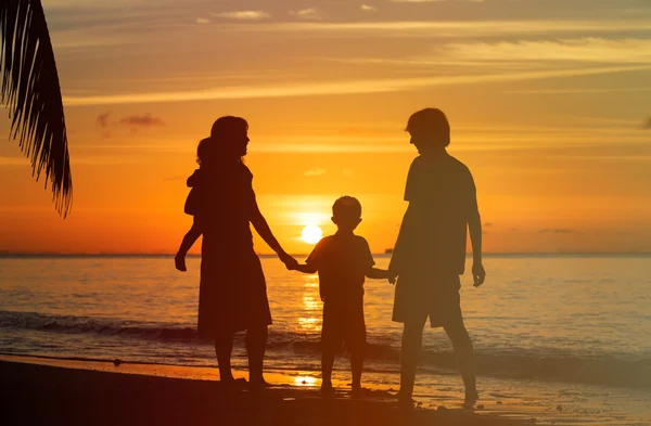 Счастливая семья с двумя детьми на закатном пляже — стоковое фото