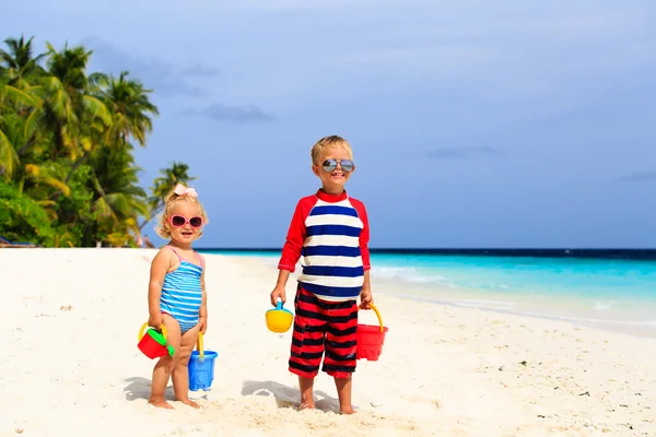 Küçük çocuk ve bebek kız tropik sahilde kum ile oynamak — Stok fotoğraf