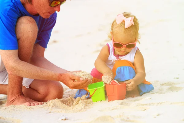 Padre e hija pequeña jugando con arena en la playa — Foto de Stock