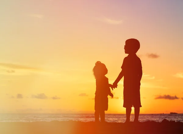Petit garçon et fille tenant la main au coucher du soleil — Photo