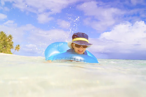 Menino com anel de vida se diverte na praia tropical — Fotografia de Stock